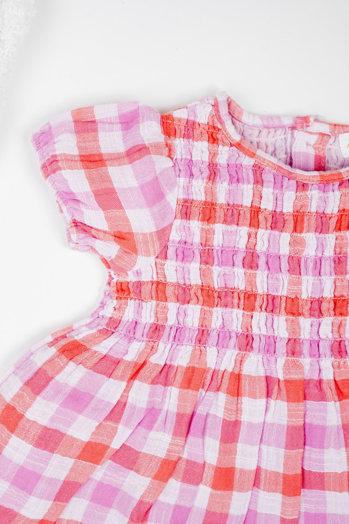 Deep red and muted purple checked, hand-smocked baby girl's dress with puff sleeves and frilled bloomers in soft double muslin organic cotton.