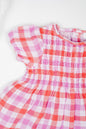 Deep red and muted purple checked, hand-smocked baby girl's dress with puff sleeves and frilled bloomers in soft double muslin organic cotton.