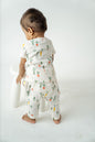 Organic cotton toddler playsuit featuring whimsical garden vegetables on a soft white background - perfect for cozy, eco-friendly everyday wear.