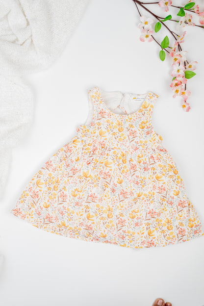 Golden Meadow Dress for girl's in soft yellow organic cotton, featuring a delicate floral print inn earthy tones, sleeveless and a breezy A-line silhouette.