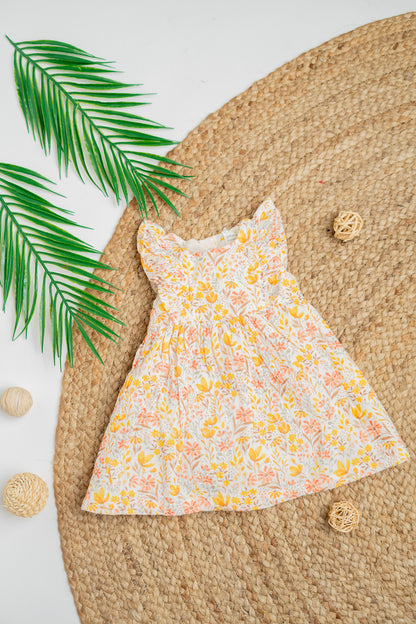 Golden Meadow infant girl's dress in soft yellow organic cotton, featuring an all-over floral print, flutter sleeves and gentle gathers for a breezy summer fit.