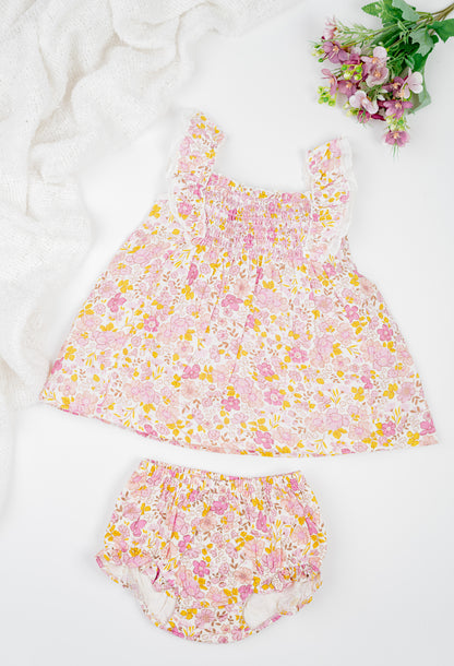 Floral cotton girl's dress with ruffled straps and matching bloomers in pink and yellow tones. Featuring a flared silhouette and shirring at the chest for breezy summer comfort. 