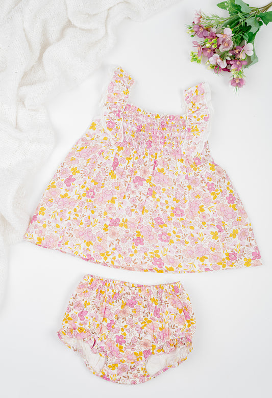 Floral cotton girl's dress with ruffled straps and matching bloomers in pink and yellow tones. Featuring a flared silhouette and shirring at the chest for breezy summer comfort. 