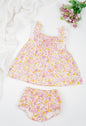 Floral cotton girl's dress with ruffled straps and matching bloomers in pink and yellow tones. Featuring a flared silhouette and shirring at the chest for breezy summer comfort. 