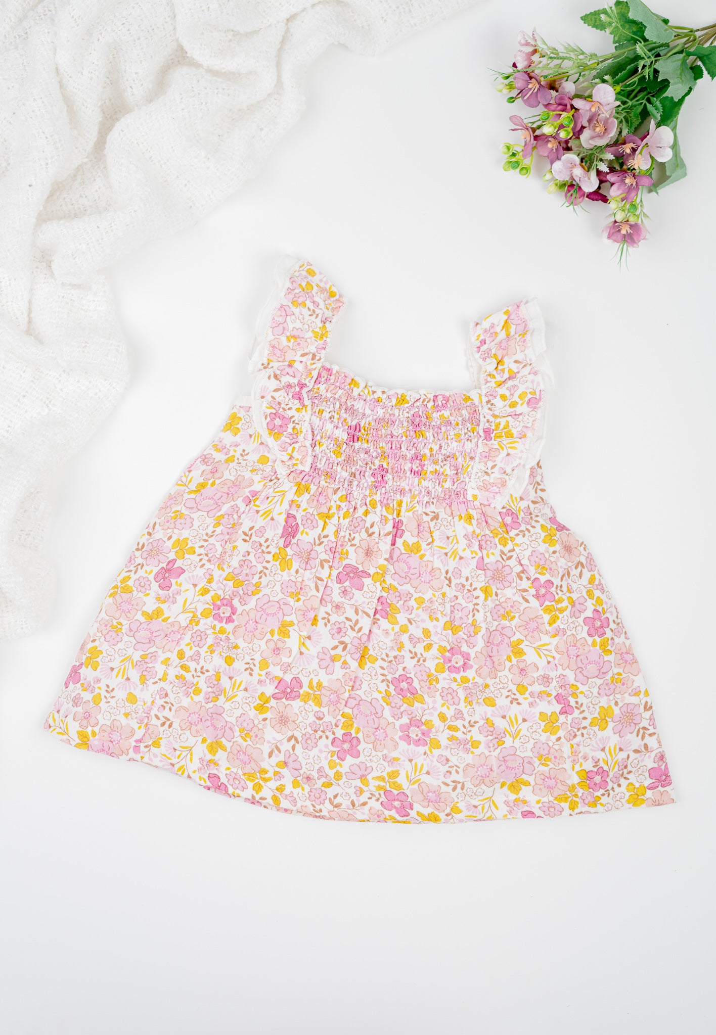 Floral cotton girl's dress with ruffled straps and matching bloomers in pink and yellow tones. Featuring a flared silhouette and shirring at the chest for breezy summer comfort. 