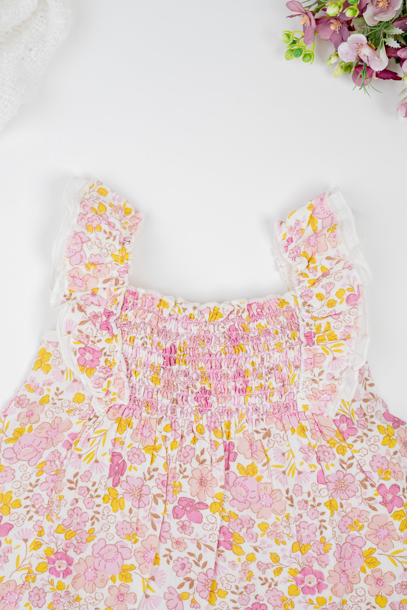 Floral cotton girl's dress with ruffled straps and matching bloomers in pink and yellow tones. Featuring a flared silhouette and shirring at the chest for breezy summer comfort. 