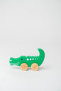 Green crocodile-shaped wooden toy with wheels for push-pull toddler play.