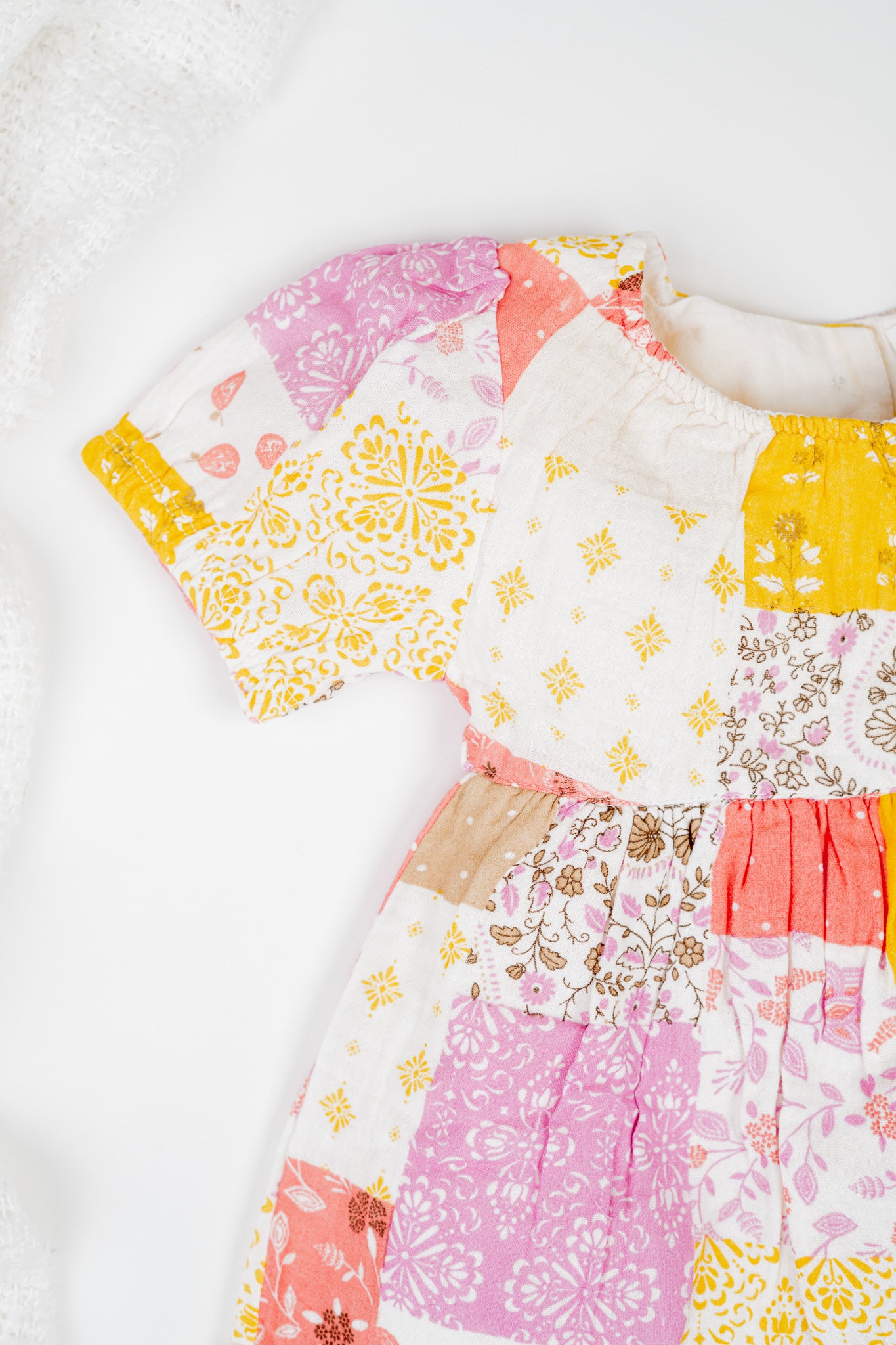 Girl's cotton patchwork printed dress with puff sleeves, featuring vibrant print, yellow and white floral and geometric prints. Comes with matching bloomers for a complete summer outfit.