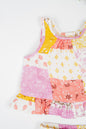 Infant organic cotton sleeveless jhabla set with colourful patchwork print in shades of pink, yellow and white, featuring floral and geometric patterns. Soft, breathable fabric designed for newborn comfort.