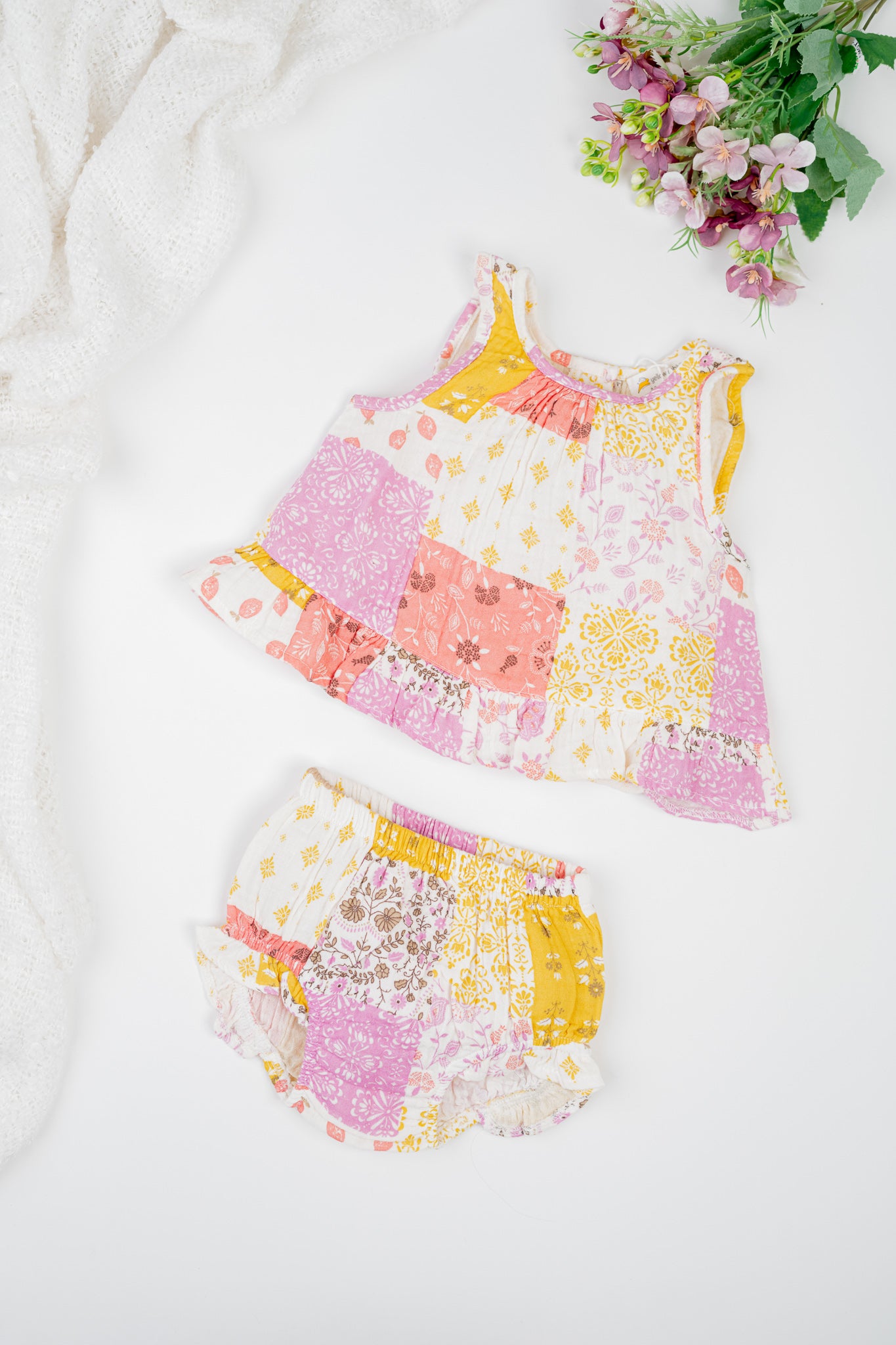 Infant organic cotton sleeveless jhabla set with colourful patchwork print in shades of pink, yellow and white, featuring floral and geometric patterns. Soft, breathable fabric designed for newborn comfort.
