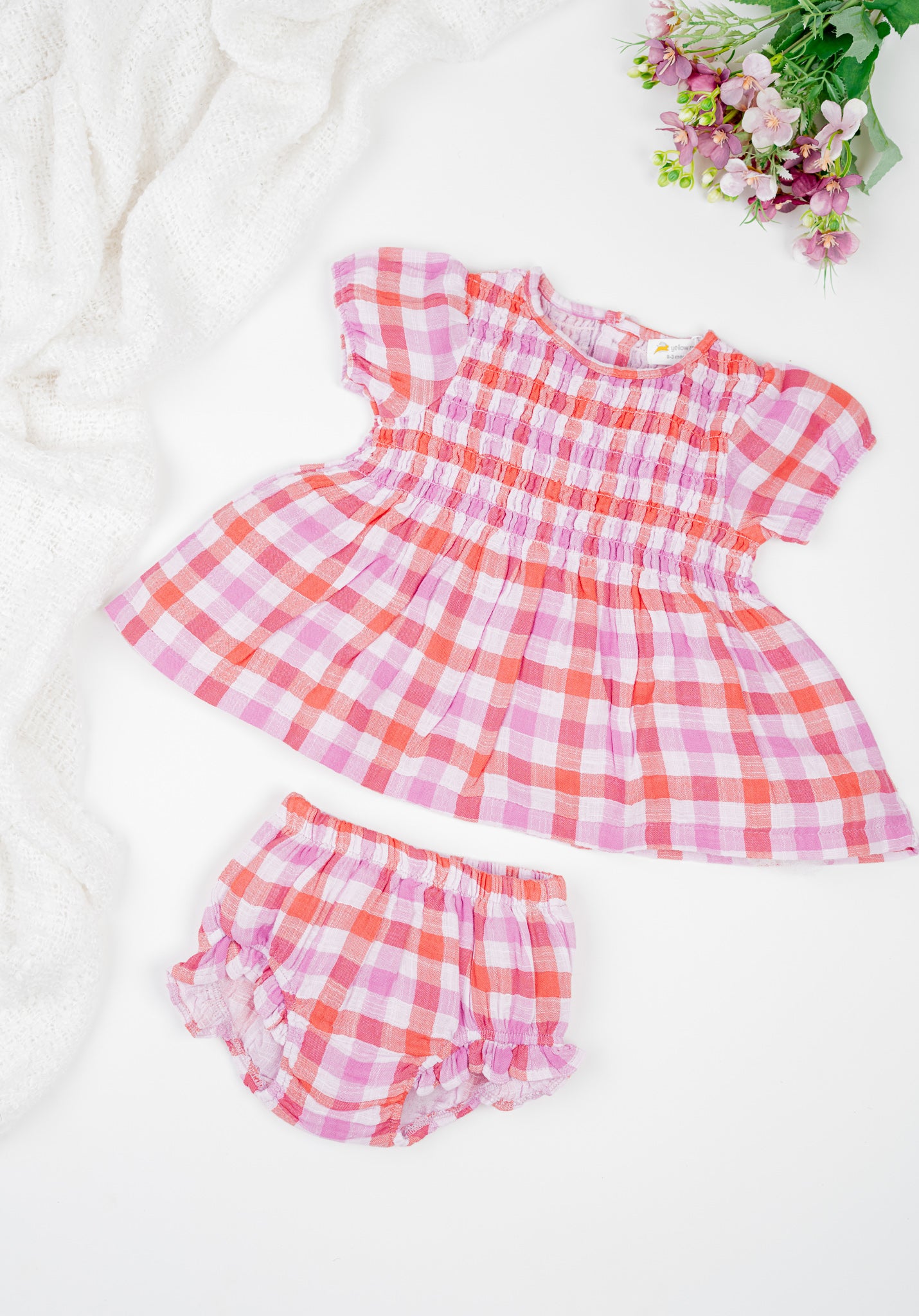 Deep red and muted purple checked, hand-smocked baby girl's dress with puff sleeves and frilled bloomers in soft double muslin organic cotton.