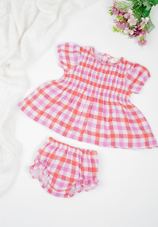 Deep red and muted purple checked, hand-smocked baby girl's dress with puff sleeves and frilled bloomers in soft double muslin organic cotton.